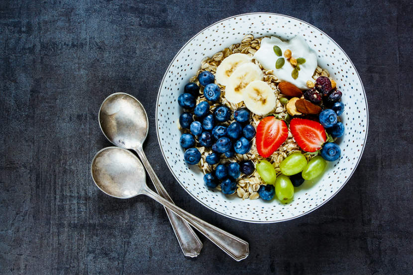 bowl of oats with fruit, nuts, seeds and yogurt on top