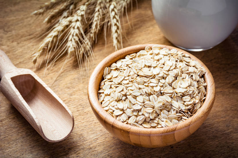 wooden bowl with oats in it with wheat on the table