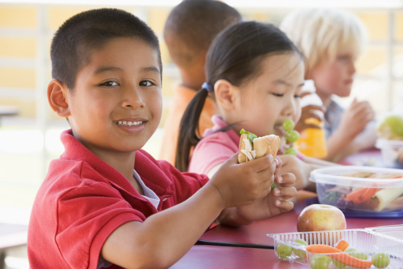 young boy eating a sandwich at school