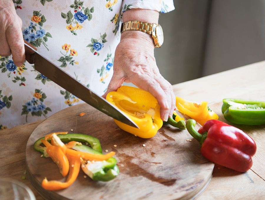 elderly woman slicing up a bell pepper in the kitchen