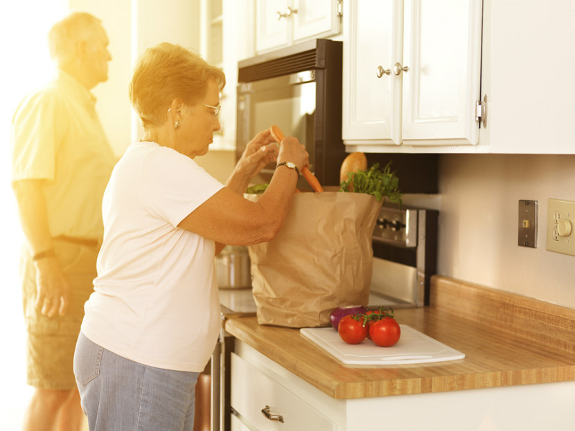 senior couple unloading groceries in their kitchen
