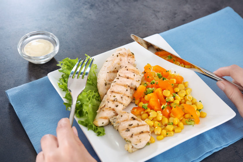 person eating grilled chicken and vegetables