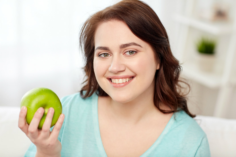 Femme tenant une pomme verte en souriant