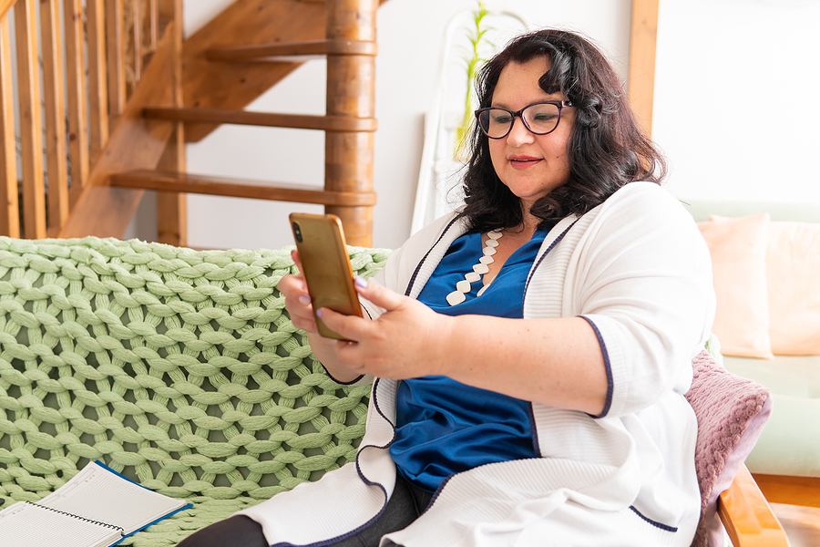 woman sitting on couch researching on phone