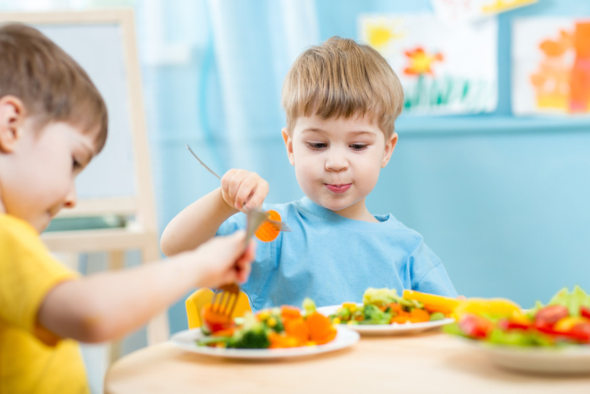 two preschool aged boys eating at a table