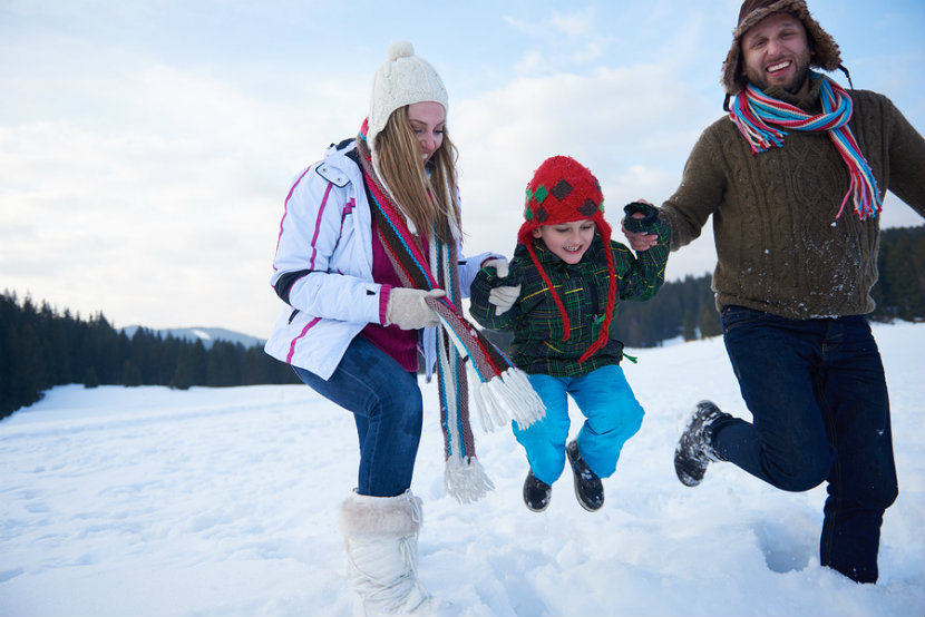 A family playing in the snow smiling and laughing