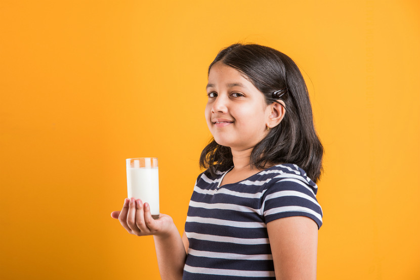 young girl holding a glass of milk or plant-based beverage