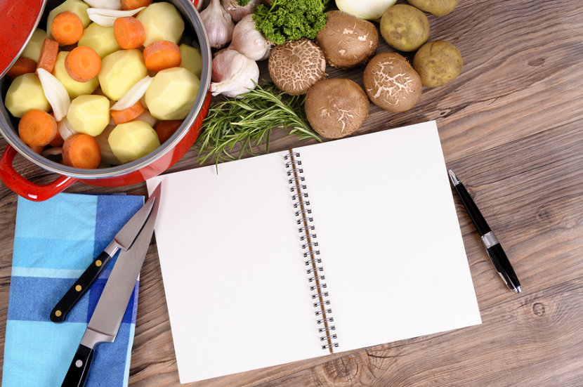 notebook in a kitchen with pots of carrots and potatoes, mushrooms and garlic