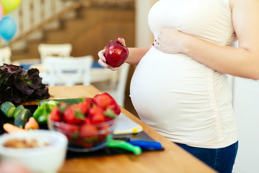 pregnant woman holding an apple
