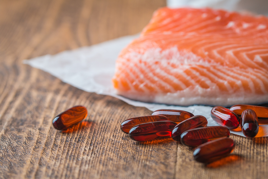 piece of fresh salmon and a fish oil capsule on a table