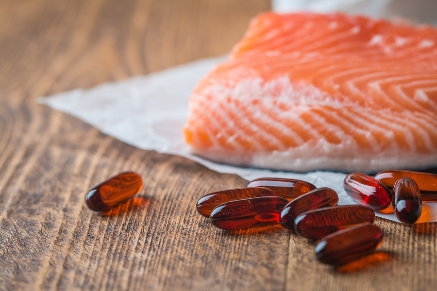 piece of fresh salmon and fish oil capsules on a table