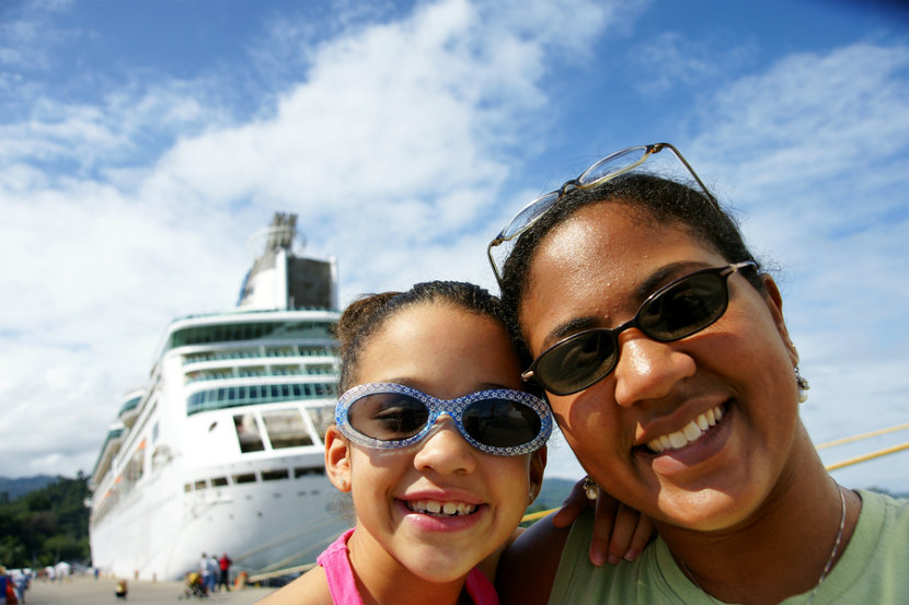 a mom and her daughter standing in front of a cruise ship
