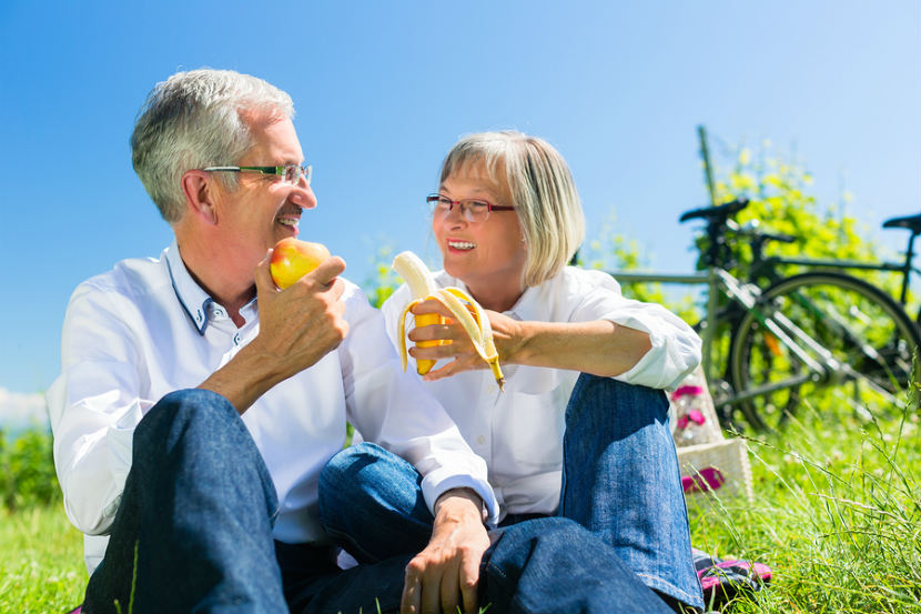 Un homme et une femme mangeant des fruits à l’extérieur après une randonnée à vélo