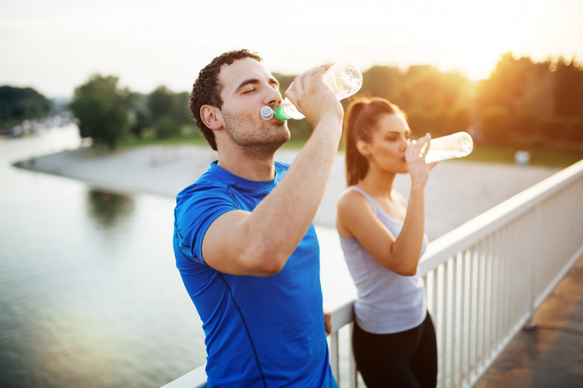 woman and man drinking bottles of water