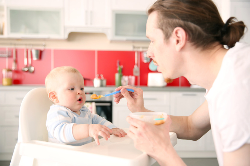 father feeding solid foods to his baby