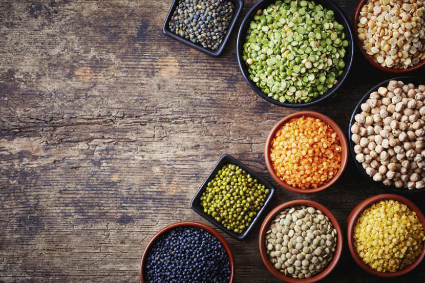 Légumineuses, pois cassés, lentilles, haricots noirs et pois chiches dans des bols sur une table.