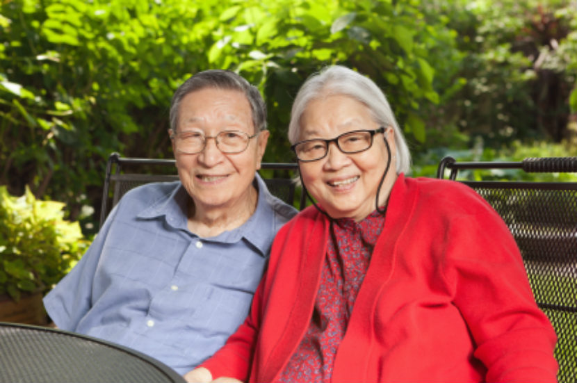 Couple âgé assis dehors, souriant