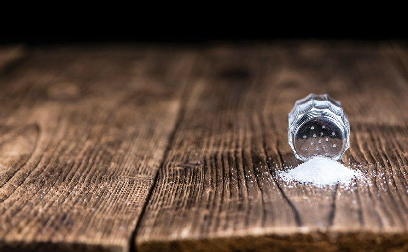saltshaker laying sideways on table with salt pouring out