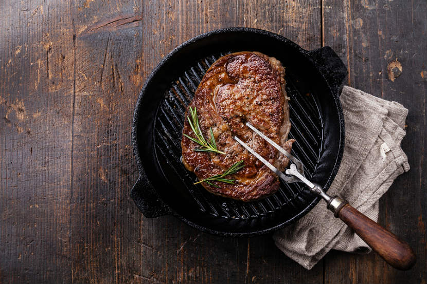 steak cooking in a cast iron pan