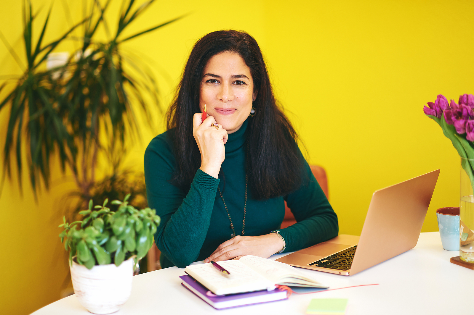 dietitian sitting at desk in yellow office with a pen in her hand