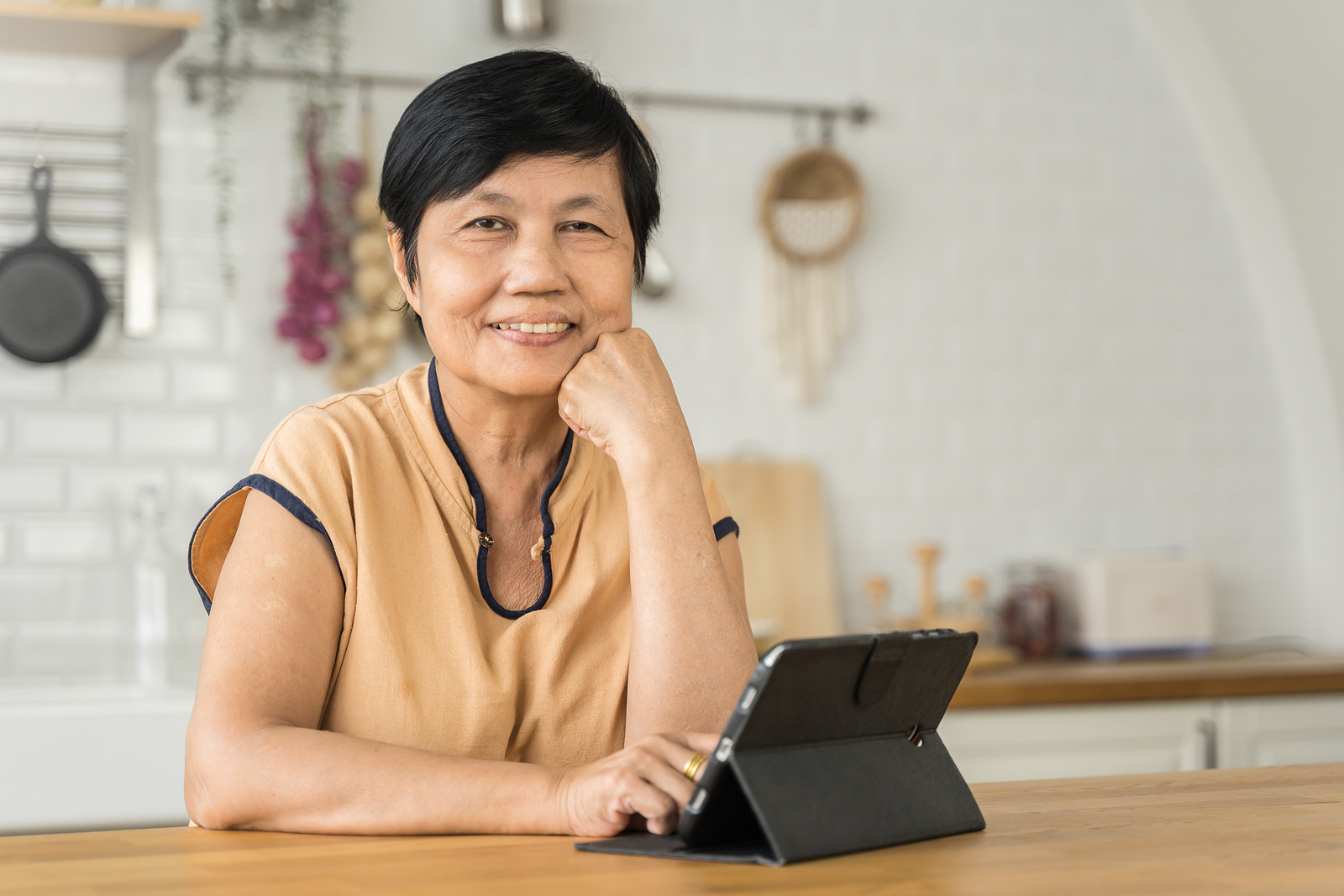 Femme souriante dans une cuisine avec une tablette