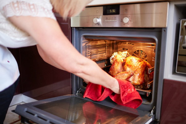 woman putting turkey in oven