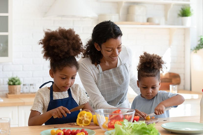mom in the kitchen teaching two little girls to cook